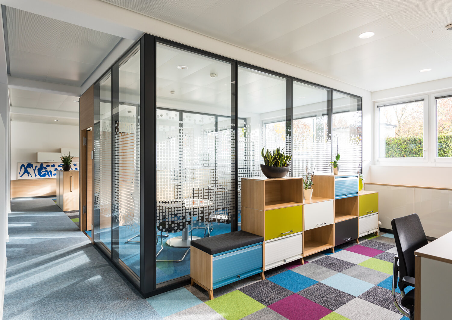 Projekt Fiducia Konferenzraum mit bedruckten Glastrennwänden und Volltür mit buntem Schrank davor