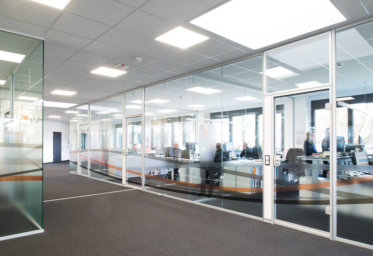 Projekt Buerkle Blick in Büro mit individuell folierten rahmenlosen Glastrennwandsystemen